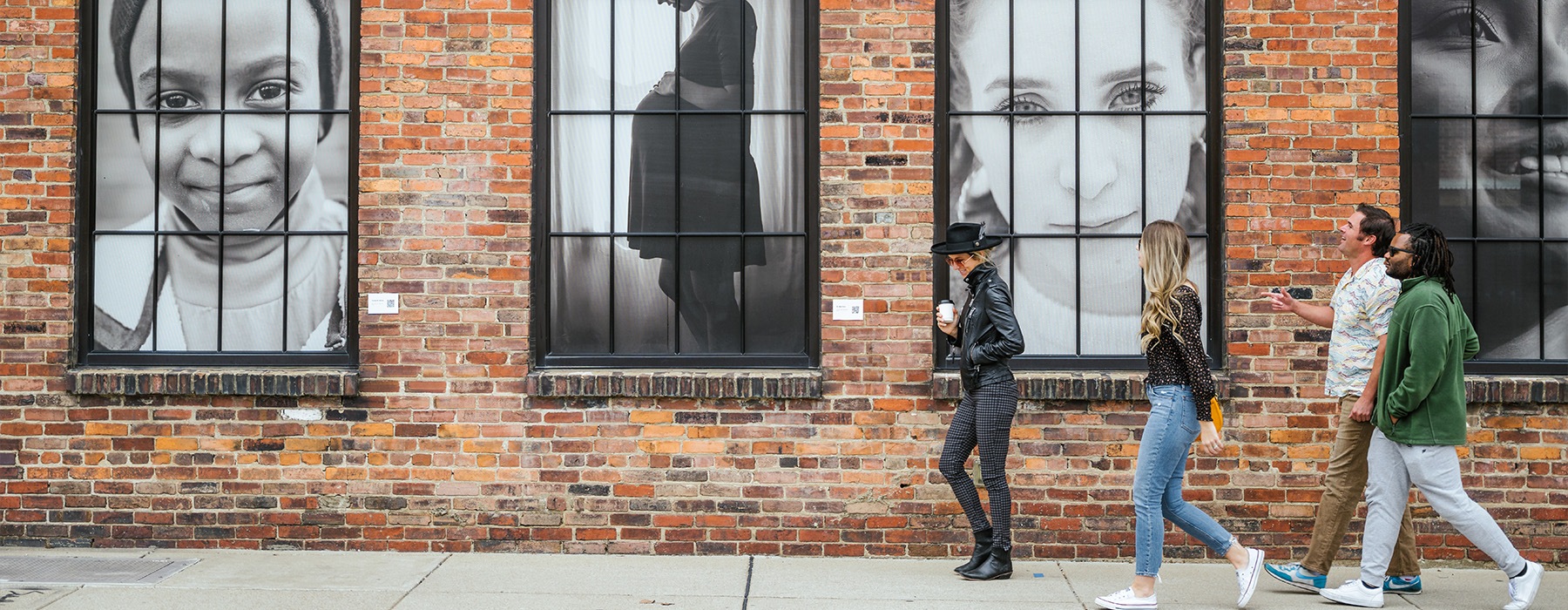 people walking down a sidewalk with art